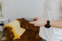 Kaboompics - Man Holding Smartphone with Black Wristwatch beside Mustard Armchair