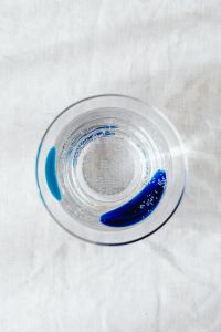 Kaboompics - Top-Down Clear Water Glass with Blue Details on White Linen, Minimal Still Life