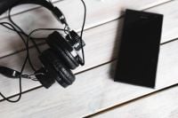 Kaboompics - Tangled Headphone Cables beside a Black Phone on White Wood