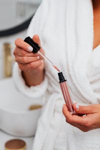 Kaboompics - Nude Lip Gloss Applicator and Open Tube Held in a Woman’s Hands
