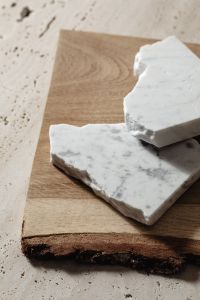 Kaboompics - White Marble Samples Styled on an Oak Board Against a Neutral Wall