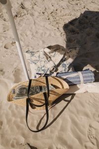 Kaboompics - Beach Umbrella Base with Straw Bag and Folded Beach Clothes