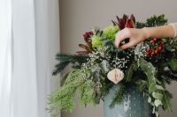 Kaboompics - Hand Placing a Paper Ornament in Festive Greenery Arrangement