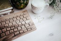 Kaboompics - Coffee Cup on Patterned Saucer beside Wooden Keyboard and Flowers