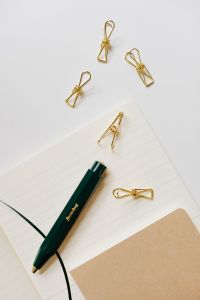 Kaboompics - Green Fountain Pen and Gold Clips on Lined Notebook with Kraft Cover, Vertical Desk Flat Lay