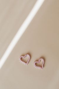 Kaboompics - Two Pearl Bead Hearts on Beige Background with Diagonal Sunlight