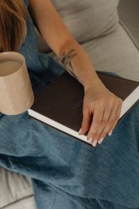 Kaboompics - Coffee Mug Beside a Closed Book on a Woman’s Denim-Clad Lap