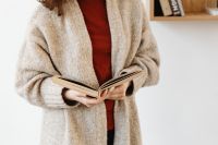 Kaboompics - Woman in a Chunky Sweater Reading an Open Book for Cozy Book Lover Content
