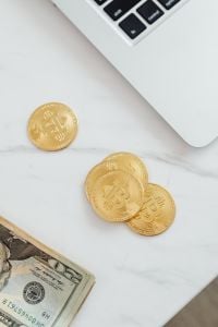 Kaboompics - Bitcoin Tokens and Dollar Bills Next to Laptop