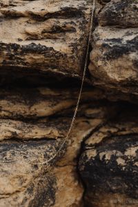 Kaboompics - Silver Necklace Looped Across Rocky Coastal Texture