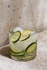 Kaboompics - Close-Up Cucumber and Lime Detox Water with Ice Against Speckled Stone, Vertical Summer Drink Background
