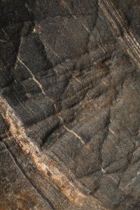 Kaboompics - Dark Charcoal Rock with Pale Mineral Veins and Angular Cracks, Dramatic Stone Texture