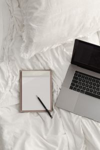 Kaboompics - Bedside Work Setup with Laptop, Blank Notebook and Pen