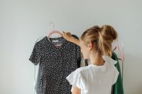 Kaboompics - Teen Girl Examining a Black Floral Blouse among Pastel Clothes, Fashion Lifestyle
