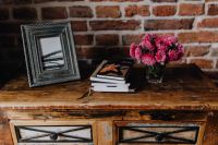 Kaboompics - Photo frame, books and pink flowers in a vase on a wooden commode