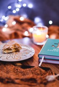 Kaboompics - Blue notebook with a candle and a sweet bun on a plate