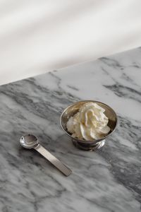 Kaboompics - Whipped Cream in a Silver Bowl with Spoon on Marble, Vertical Dessert Still Life