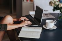 Kaboompics - Woman using a laptop by a round breakfast table