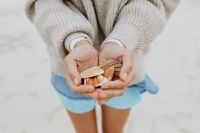 Kaboompics - Close-Up of Seashells Cradled in Both Hands against a Soft Beach Background