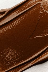 Kaboompics - Close-Up Dark Brown Foundation Cream with Curved Smear and Textured Edge, Rich Makeup Swatch Background