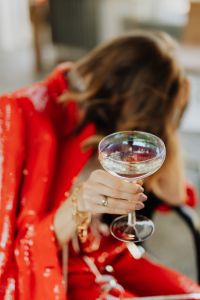 Kaboompics - Woman in red pants and a white shirt  is sitting on a chair with glass