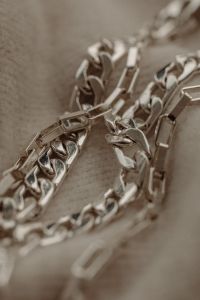 Kaboompics - Layered Silver Chain Links on Textured Taupe Fabric