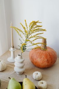 Kaboompics - Orange Pumpkin with Mini White Pumpkins, Goldenrod, Taper Candle and Fruit on Beige Linen