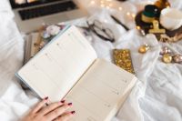 Kaboompics - Top-Down View of a Woman Planning in an Open 2018 Organizer on White Bedding