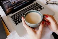Kaboompics - Close-Up of a Gray Coffee Mug in a Woman’s Hands over a Laptop Keyboard during a Remote Work Break