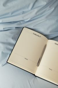 Kaboompics - Open Planner on Blue Bedding With Copy Space
