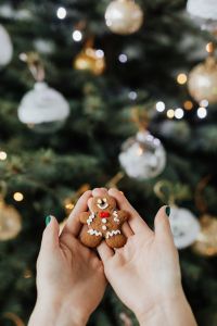 Kaboompics - Hands Holding Gingerbread Cookie by Christmas Tree