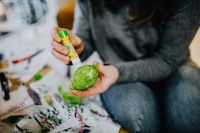 Kaboompics - Hands Painting a Green Easter Egg at a Craft Table