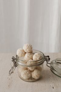 Kaboompics - Glass Jar of Coconut Truffles beneath Sheer Curtains, Vertical Minimal Food Background with Copy Space