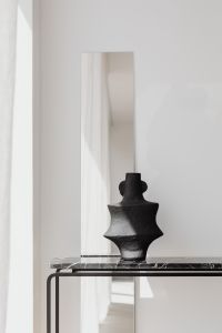Kaboompics - Black Sculptural Vase Reflected In Marble Console Mirror