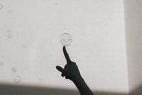 Kaboompics - Silhouette Hand Touching a Soap Bubble on White Wall with Copy Space