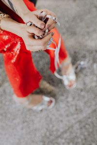 Kaboompics - Hands Gathering Silver Confetti Streamers over Red Sequin Trousers