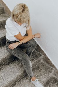 Kaboompics - Blonde Woman in White T-Shirt and Gray Jeans Sitting on Stairs, Relaxed Lifestyle Editorial