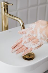 Kaboompics - Soapy Hands at a White Vessel Sink with Brass Fixtures, Vertical Hygiene Tutorial