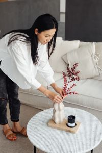 Kaboompics - Woman Styling a Vase on a Living Room Coffee Table