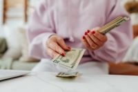 Kaboompics - Faceless Woman Counting Dollar Bills at a Table