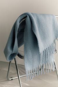 Kaboompics - Pale Blue Fringed Scarf on a Transparent Chair for Cozy Winter Decor