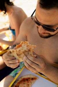 Kaboompics - Man Eating Pizza with a Woman in the Background