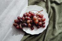 Kaboompics - Overhead Red Grapes on a White Plate with Gray and Green Linen