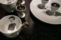 Kaboompics - White Tea Cup with Portrait Illustration and Matching Saucer on a Dark Table