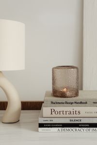Kaboompics - Ceramic Table Lamp and Lit Votive on Design Books, Soft Neutral Home Decor