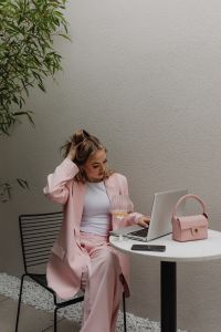 Kaboompics - Woman Adjusting a Pale Pink Blazer Beside a Laptop