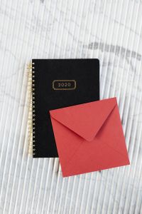 Kaboompics - Red Envelope and Black 2020 Planner on White Marble, Stationery Mockup