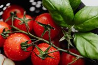 Kaboompics - Close-Up Cherry Tomatoes and Fresh Basil Against Dark Colander