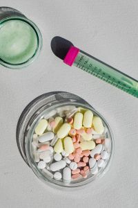 Kaboompics - Green Sample Tube Beside Petri Dish and Tablets