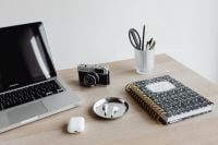 Kaboompics - Laptop, Camera, AirPods and Notebook on Desk with Copy Space